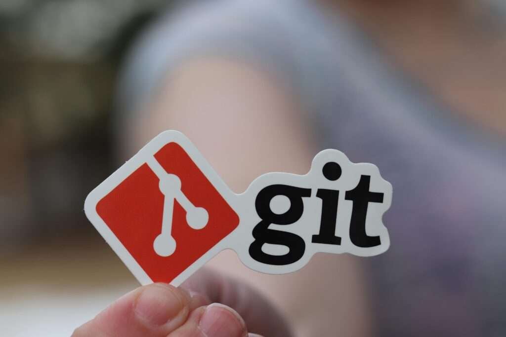 Close-up of a person holding a Git sticker, emphasizing software development.